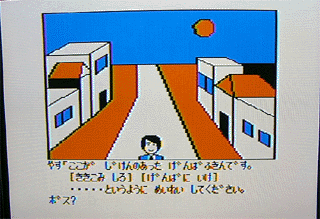 Image tirée de la première version de « The Portopia Serial Murder Case », montrant une rue avec un personnage, et du texte en japonais en dessous de l'image.
