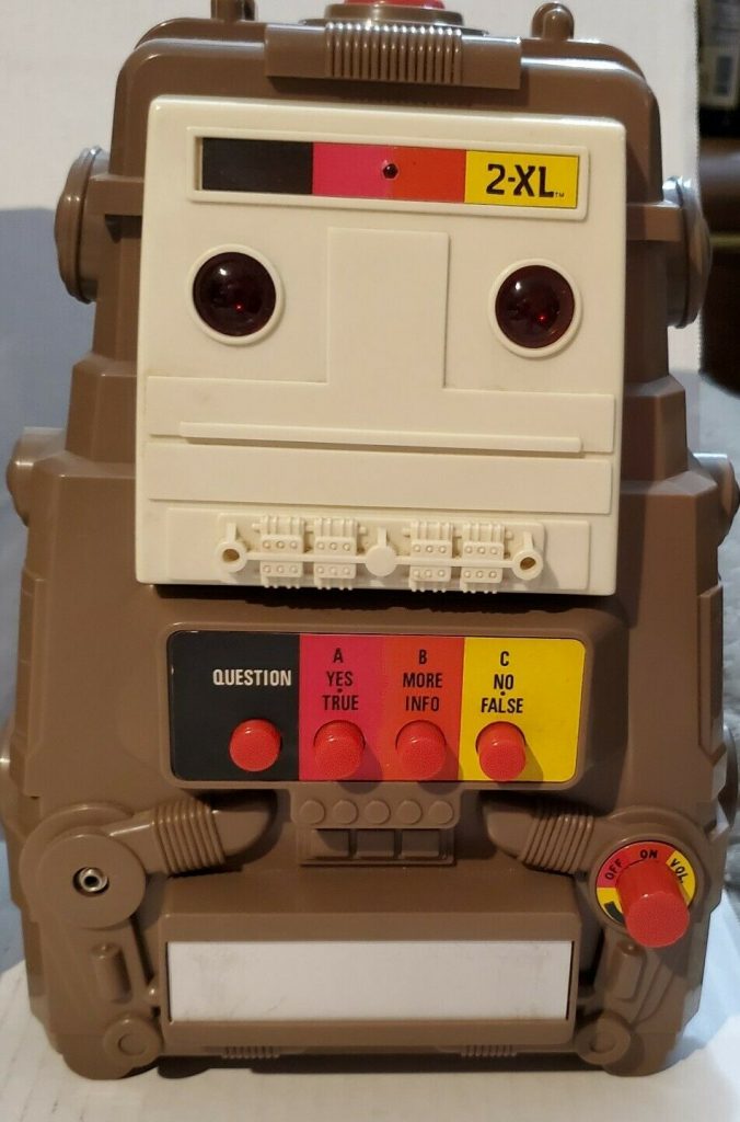 Photo d'un appareil marron avec un lecteur cassette et des boutons intitulés « question », « yes », « more », « no ».